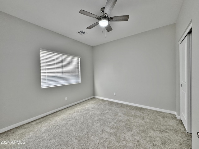 unfurnished bedroom with light carpet, a closet, and ceiling fan