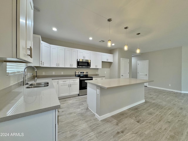 kitchen featuring stainless steel appliances, sink, white cabinets, a center island, and hanging light fixtures