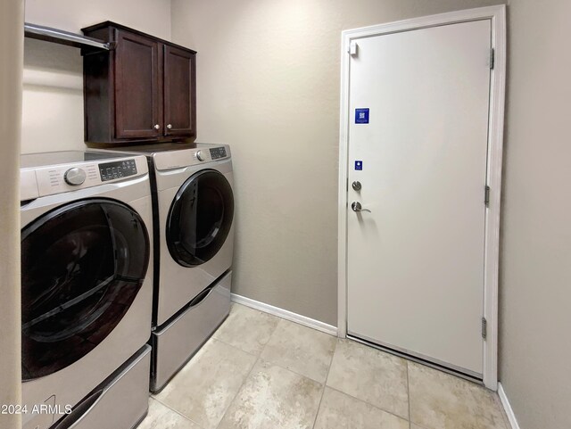 laundry area featuring washing machine and clothes dryer, cabinets, and light tile patterned floors