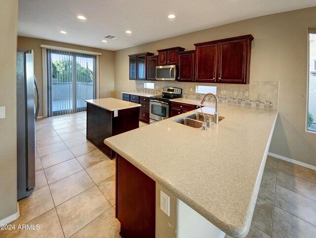 kitchen featuring light tile patterned floors, sink, kitchen peninsula, a kitchen island, and stainless steel appliances