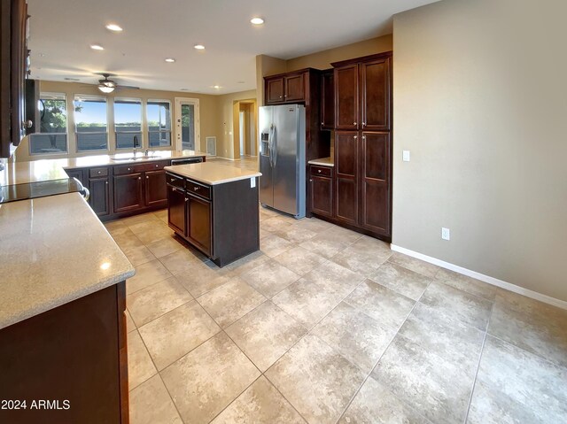 kitchen with ceiling fan, sink, a kitchen island, dark brown cabinets, and appliances with stainless steel finishes