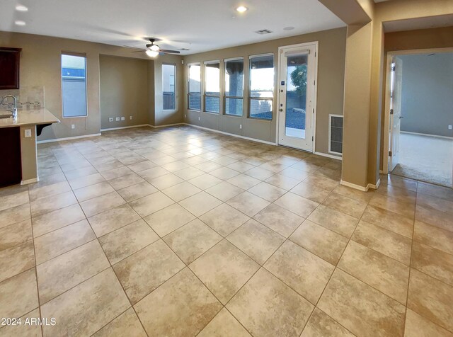 unfurnished living room featuring ceiling fan, plenty of natural light, and light tile patterned flooring