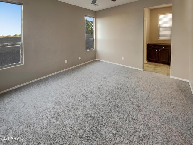 unfurnished bedroom with ensuite bath, light carpet, and ceiling fan