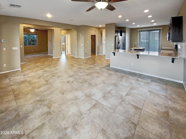 kitchen featuring ceiling fan, appliances with stainless steel finishes, a healthy amount of sunlight, and a breakfast bar area