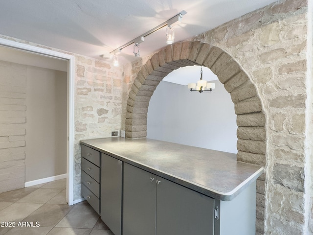 7770 E Camelback Rd Unit 23, Scottsdale, AZ 85251 - kitchen with rail lighting, light tile patterned floors, arched walkways, a chandelier, and a peninsula