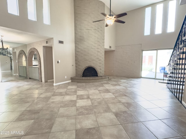 7770 E Camelback Rd Unit 23, Scottsdale, AZ 85251 - unfurnished living room with a towering ceiling, a large fireplace, a ceiling fan, baseboards, and stairs