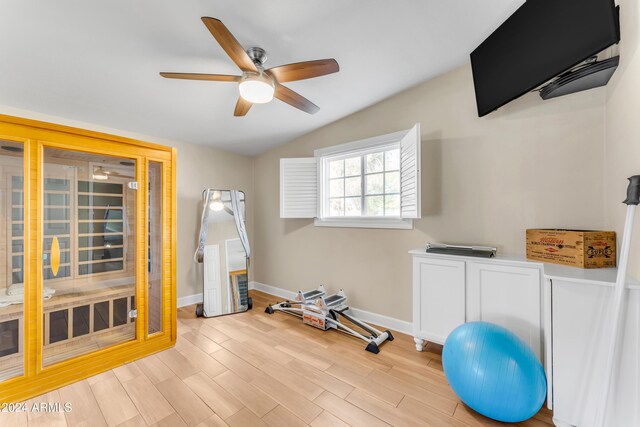 workout area with ceiling fan, vaulted ceiling, and light hardwood / wood-style flooring