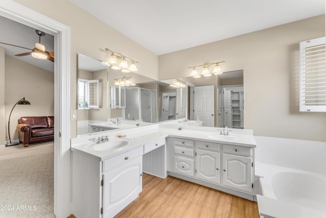 bathroom with hardwood / wood-style flooring, ceiling fan, a tub, and vanity