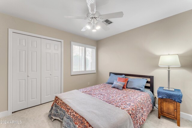 bedroom with ceiling fan, a closet, and light carpet