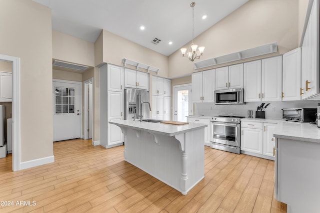 kitchen featuring white cabinetry, high vaulted ceiling, a chandelier, and appliances with stainless steel finishes