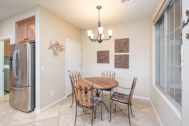 dining area featuring washer / dryer, light tile patterned floors, and an inviting chandelier