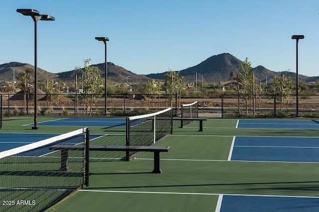 view of tennis court with fence and a mountain view