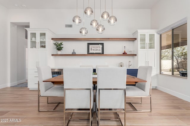 dining area with visible vents, light wood-style flooring, and baseboards