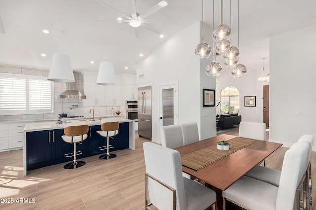 dining area with recessed lighting, light wood-style floors, and high vaulted ceiling