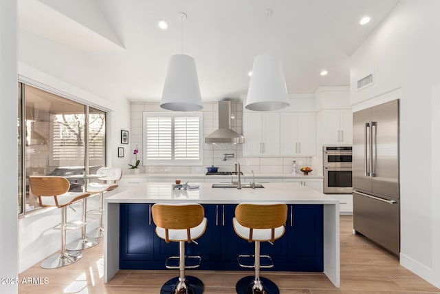 kitchen with tasteful backsplash, visible vents, light countertops, range hood, and stainless steel appliances