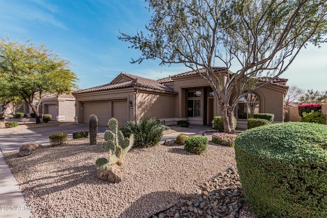 view of front of property with concrete driveway, a tiled roof, an attached garage, and stucco siding