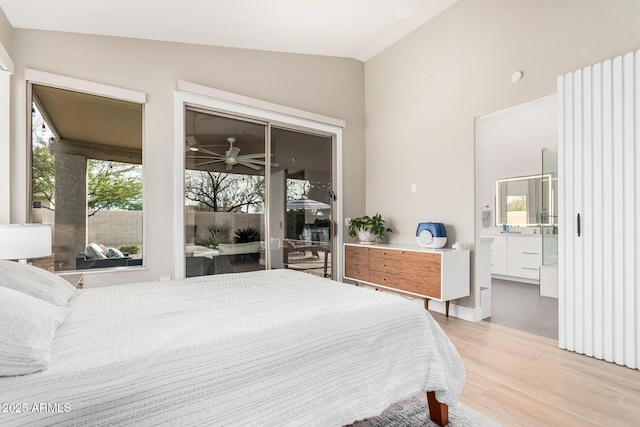 bedroom with vaulted ceiling, light wood-style floors, and ensuite bathroom