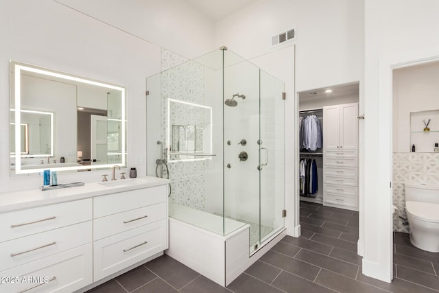 bathroom featuring visible vents, toilet, a stall shower, and vanity