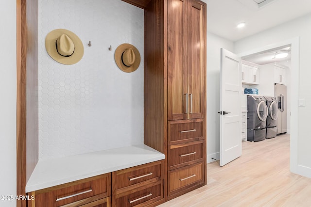 hallway featuring light wood-type flooring, baseboards, and separate washer and dryer