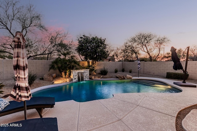 pool at dusk with a patio area, a fenced in pool, and a fenced backyard