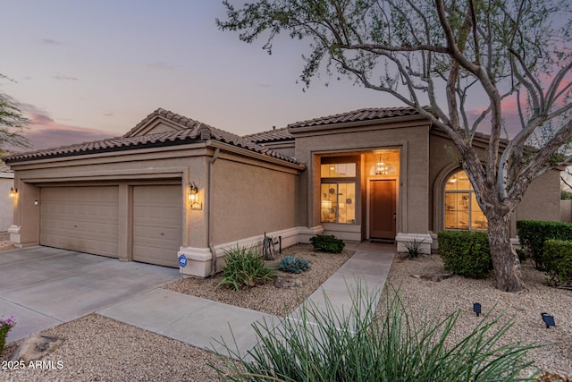 mediterranean / spanish house featuring stucco siding, a tiled roof, concrete driveway, and a garage