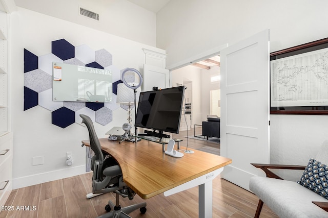 office area with visible vents, beamed ceiling, baseboards, and wood finished floors