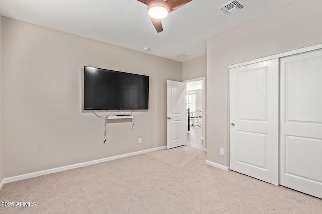 unfurnished bedroom with ceiling fan, a closet, and light carpet