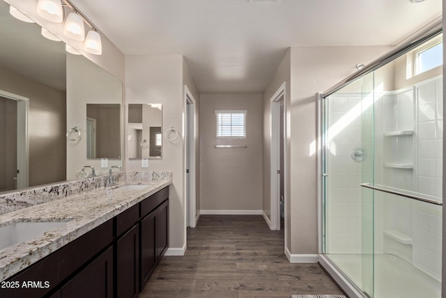 bathroom with wood-type flooring, a healthy amount of sunlight, an enclosed shower, and vanity