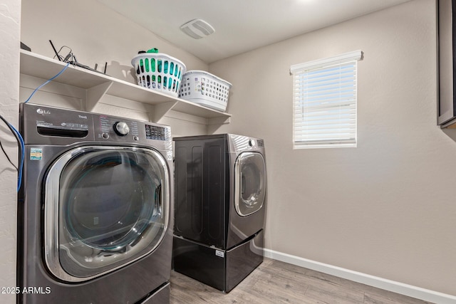 clothes washing area with hardwood / wood-style flooring and independent washer and dryer