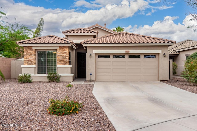 mediterranean / spanish house with an attached garage, concrete driveway, stucco siding, stone siding, and a tiled roof