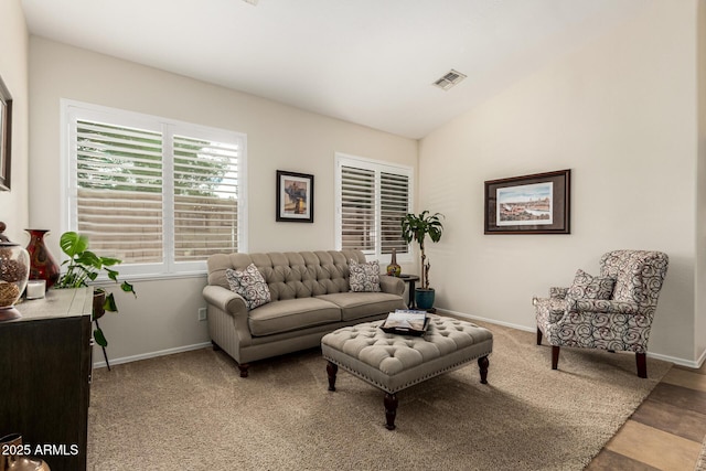 carpeted living area featuring baseboards and vaulted ceiling