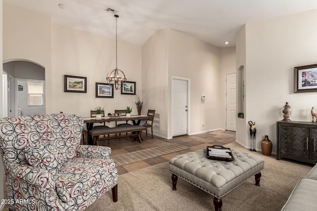 living area featuring a high ceiling, arched walkways, a chandelier, baseboards, and tile patterned floors