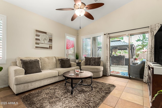 living room with a ceiling fan, lofted ceiling, light tile patterned floors, and baseboards