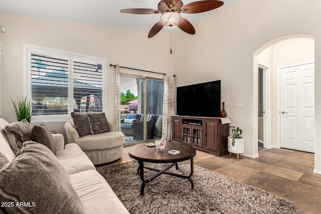 living area with arched walkways, ceiling fan, and baseboards