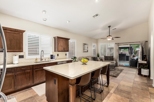 kitchen featuring a sink, backsplash, a kitchen island, vaulted ceiling, and stainless steel appliances