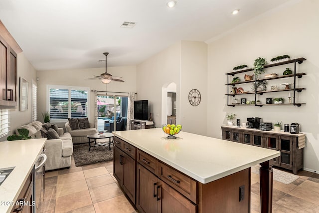 kitchen with lofted ceiling, arched walkways, a ceiling fan, light countertops, and open floor plan