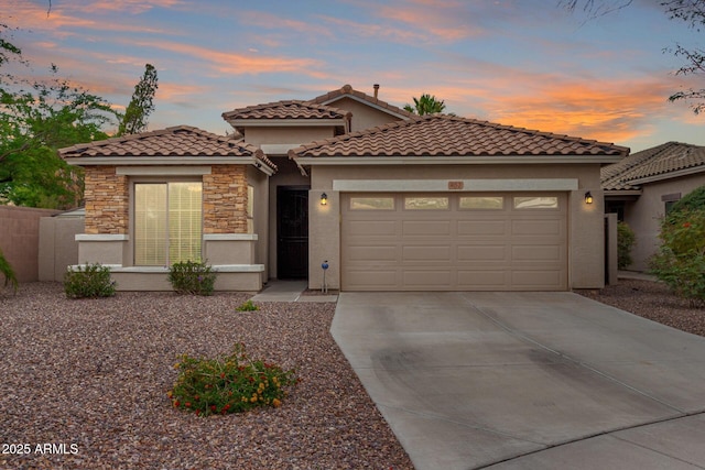 mediterranean / spanish house with stucco siding, a garage, driveway, and stone siding