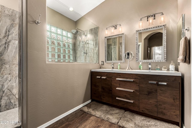 full bath with wood finished floors, walk in shower, double vanity, and baseboards