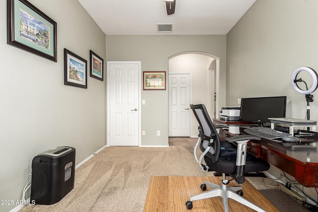 carpeted office featuring arched walkways and baseboards