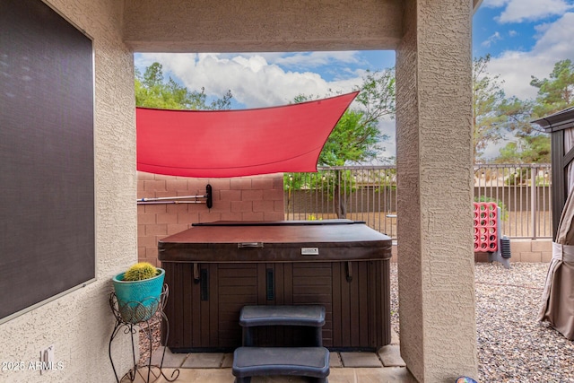 view of patio / terrace with a hot tub and fence