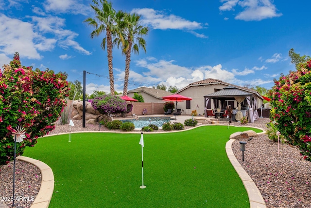 fenced backyard featuring a gazebo, a putting area, and a patio area