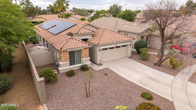 mediterranean / spanish-style home with stucco siding, a garage, a tile roof, driveway, and solar panels