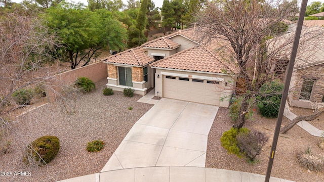 mediterranean / spanish home with an attached garage, concrete driveway, stucco siding, fence, and a tiled roof
