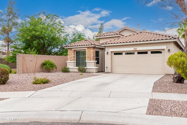 mediterranean / spanish-style house with stucco siding, an attached garage, concrete driveway, stone siding, and fence