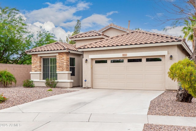 mediterranean / spanish home with a garage, driveway, fence, stucco siding, and stone siding