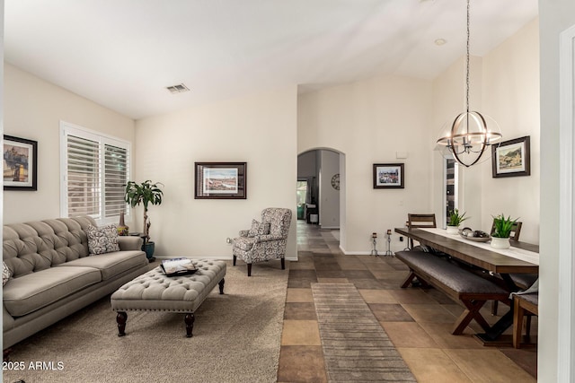 living area with arched walkways, a chandelier, high vaulted ceiling, and baseboards