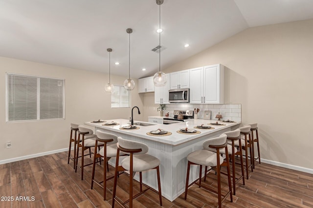 kitchen with stainless steel appliances, a sink, backsplash, and dark wood-style floors