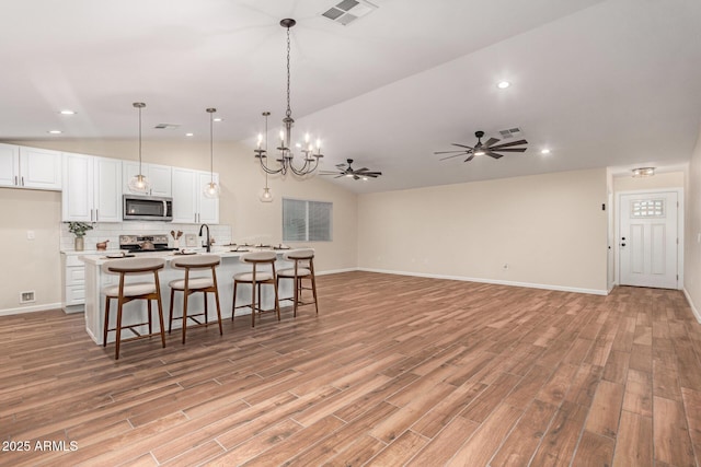 kitchen featuring visible vents, a ceiling fan, lofted ceiling, stainless steel appliances, and white cabinetry