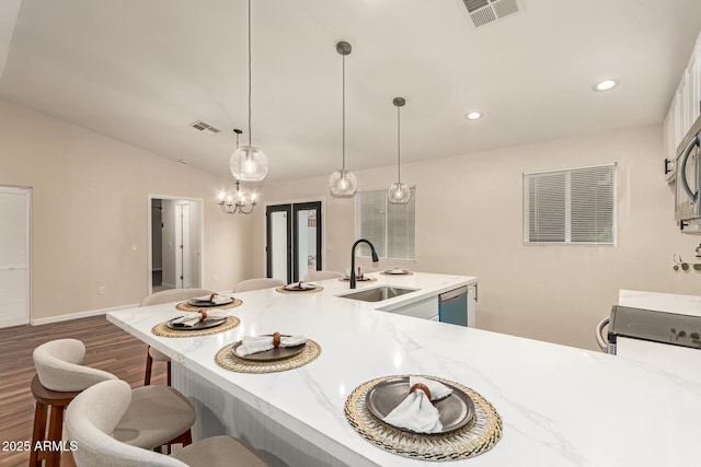 kitchen featuring vaulted ceiling, visible vents, a breakfast bar, and a sink