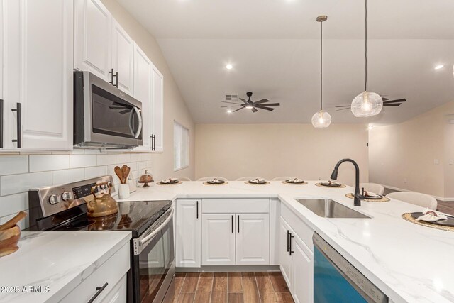 kitchen featuring stainless steel appliances, a sink, white cabinets, backsplash, and wood tiled floor